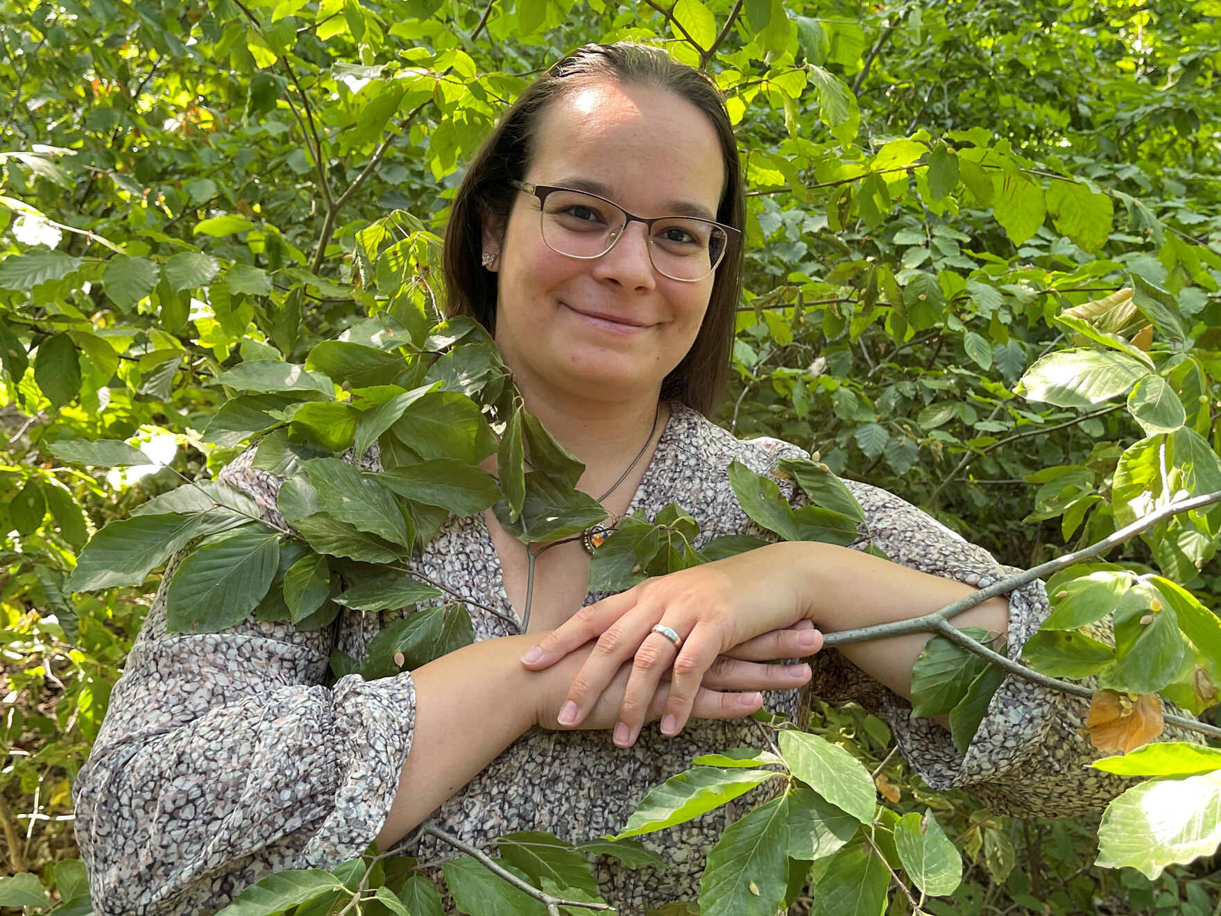 Katja Schreiber lächelt zwischen grünen Zweigen