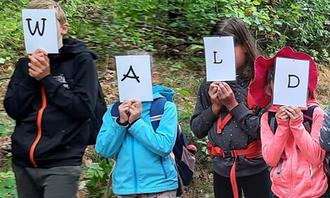 Kinder mit Buchstabenschildern, die das Wort Wald zeigen