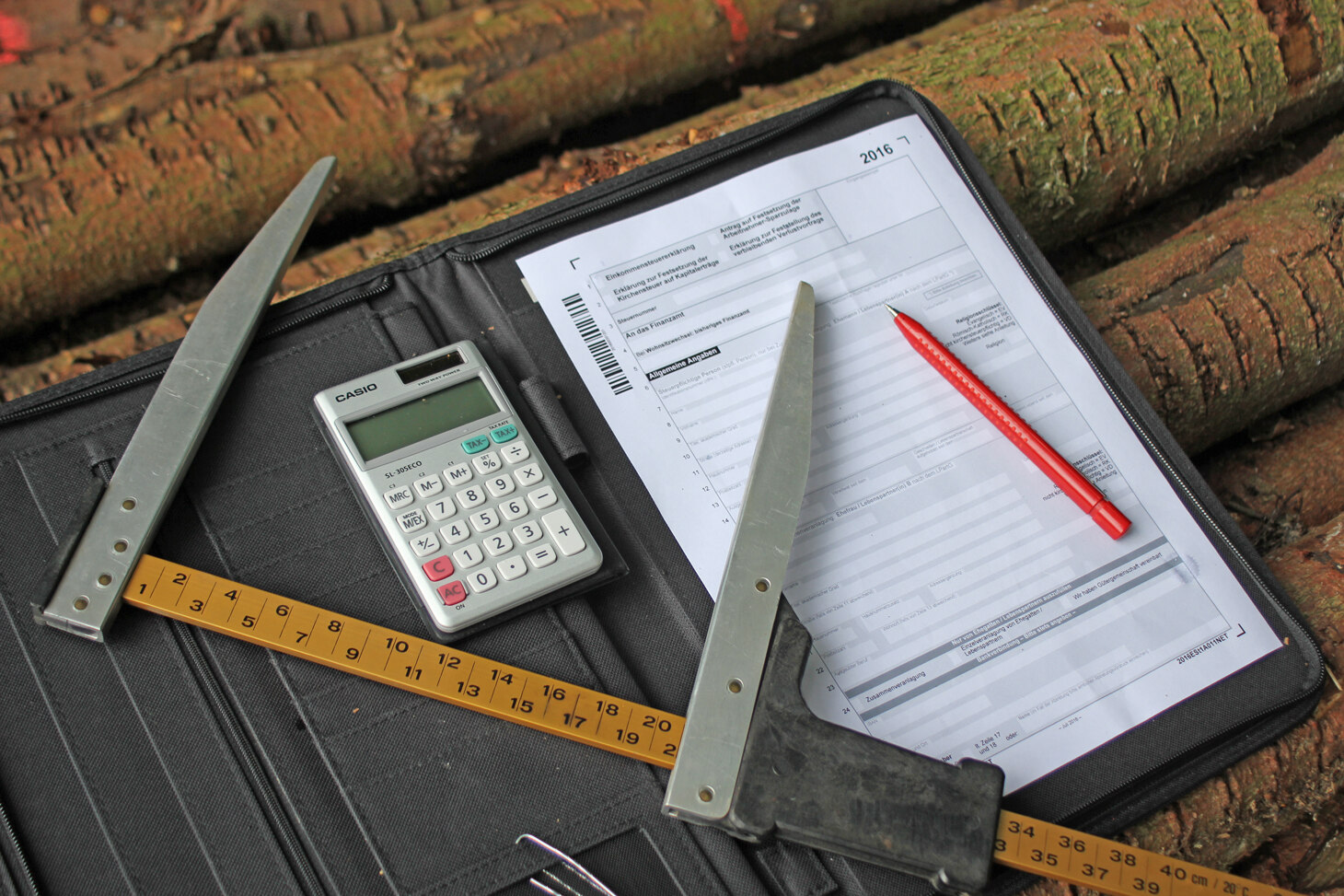 Stilleben von Kluppe, Taschenrechner und Stift auf einem leeren Formular zur Steuererklärung.