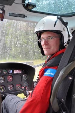 Der Pilot mit Helm sitzt im Helikopter.