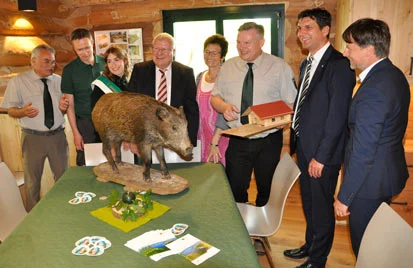Die G&auml;ste an einem Tisch mit dem Pr&auml;parat eines Wildschweines