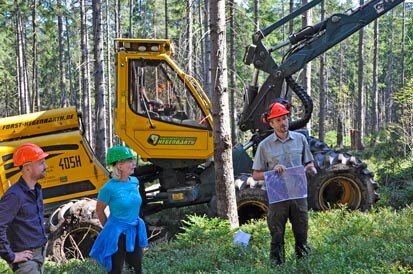 Ein Mitarbeiter mit einem Luftbild vor einem Harvester.