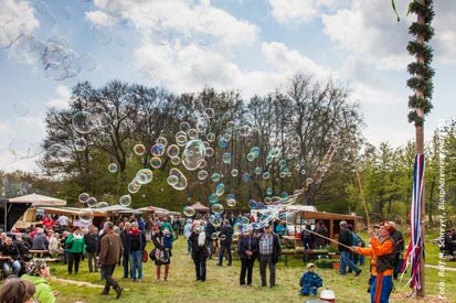 Über den Besuchern des Marktes steigen bunte große Seifenblasen auf