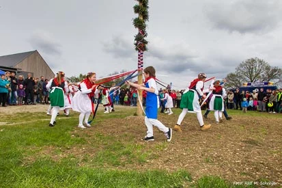 Sch&uuml;ler in bunten Trachten beim Tanz am Maibaum