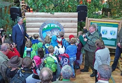 Minister Schmidt (links) mit Schulkindern vor dem Logo des OberHolzHauses.