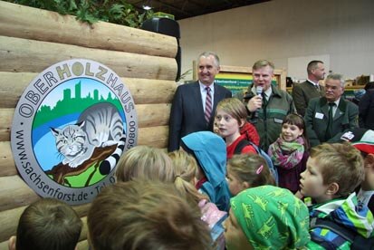 von links nach rechts: Staatsminister Thomas Schmidt, Forstdirektor Andreas Padberg, Landesforstpräsident Prof. Dr. Hubert Braun vor dem Logo des Oberhozhauses und Schulkindern