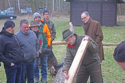 Andreas Schwientek vor Zuhörern mit einem Kiefernbrett.