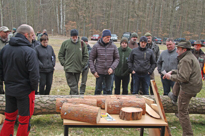 Andreas Schwientek mit Zuhörern vor einem Tisch mit Holzstücken.