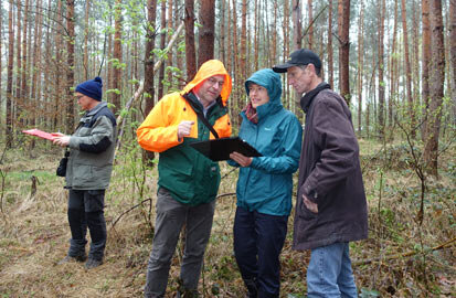 Drei Tagungsteilnehmer bei der Diskussion im Wald