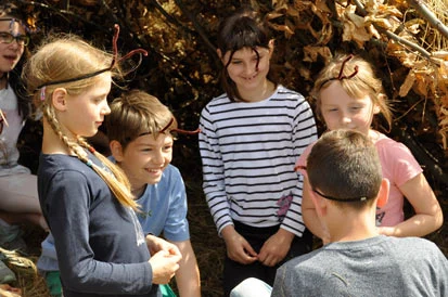 Lachende Kinder, die sich kleine F&uuml;hler aus Draht auf die Stirn gesetzt haben