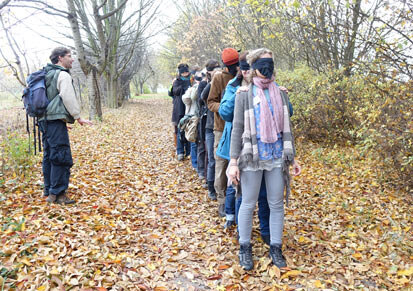 Worshop-Teilnehmer mit verbundenen Augen auf einem Waldweg