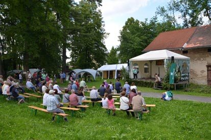 Zahlreiche Besucher sitzen auf Bänken vor einer Bühne