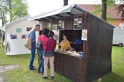 Besucher stehen vor einer Holzhütte, in der Pilzberater Pilze präsentieren