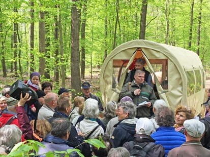 Forstdirektor Andreas Padberg begrüßt die Wanderer von einem Planwagen aus.