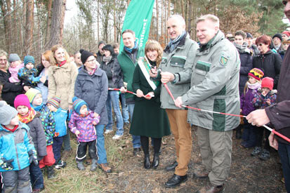 Minister Schmidt und Forstbezirksleiter Padber durchtrennen gemeinsam mit der Waldkönigin ein Absperrband.